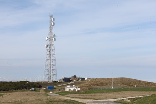 The Kennaook / Cape Grim Baseline Air Pollution Station from a distance. The site is situated on the coastline, with a phone tower soaring above the station. 
