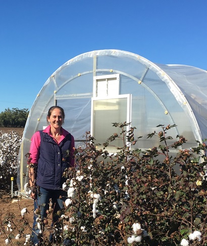 Katie Broughton stands outside a glasshouse surrounded by a field of cotton in Narrabri, northern NSW.