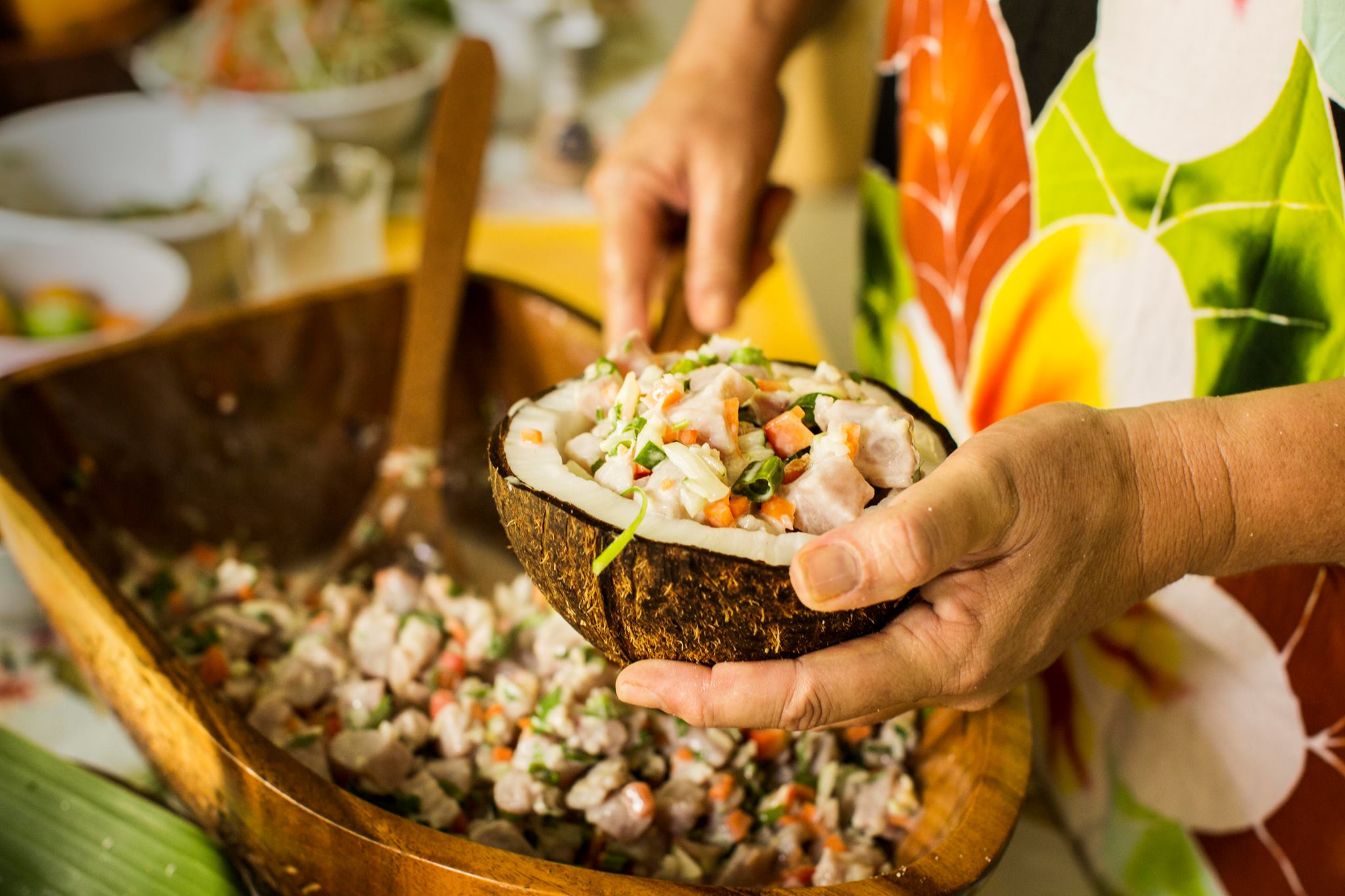 A bowl of ika mata, traditional Pacific dish of raw tuna, coconut milk and lemon or lime juice is being scooped into a coconut shell