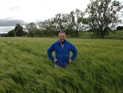 Image of Dr Greg Tanner standing in a field of green barley