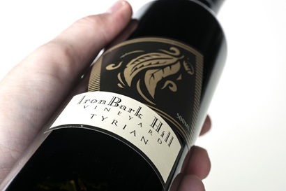 close shot of a bottle of Tyrian wine being held horizontally to show label.