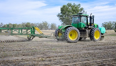 A tractor moving through  a field with crop stubble