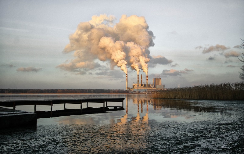 A factory spewing out steam and a beach