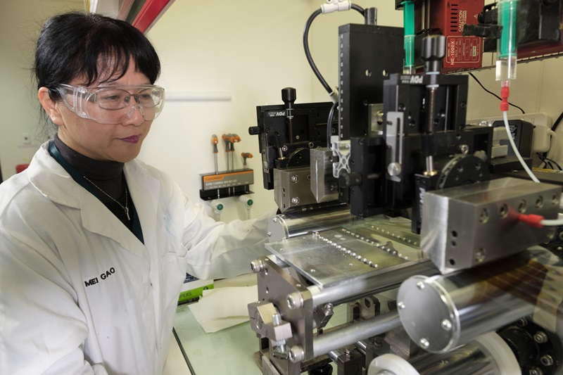 Lady looking at a machine in the Flexible Solar lab.