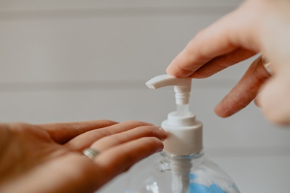 Pushing pump bottle of hand sanitiser onto hand