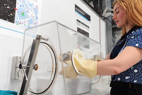 Woman working on material using glove box equipment