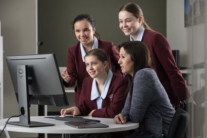Three female students and teacher looking at computer