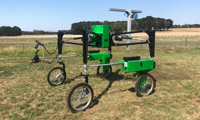 Image of green and black machine with four wheels in crop. 