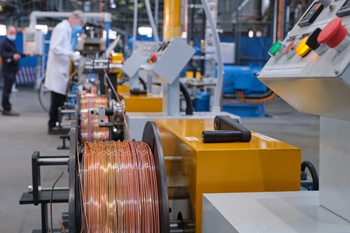 Image shows a large machine with spools of orange coloured wire.