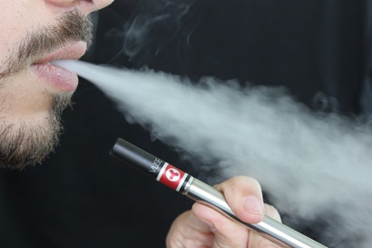 close-up image of a man blowing smoke from an e-cigarette