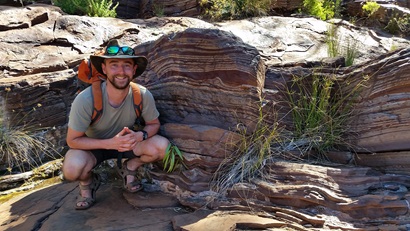 Sam Spinks squatting down by a rock