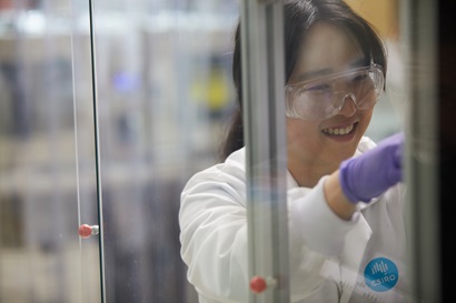 Woman in safety glasses and gloves working in a lab