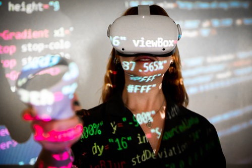 A woman with VR goggles, handset and code projected over her body