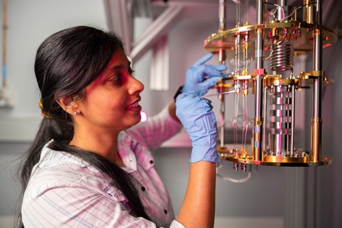 A female student with dark hair works on a golden quantum computer. 