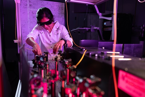 Female student with dark hair in a light shirt works on quantum machiney. 