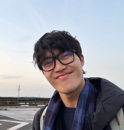 A young male with glasses smiling at the camera.