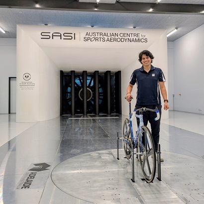 A male standing by a bicycle in a wind tunnel set up at the SASI Australian Centre for Sports Aerodynamics