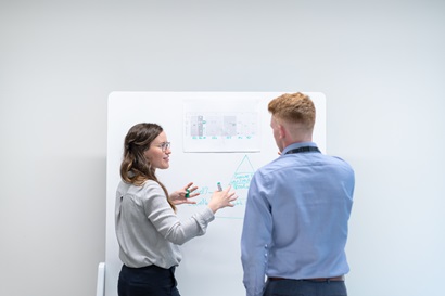 woman and man standing at whiteboard discussing plannning