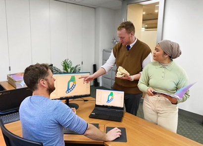 Three people looking at a computer monitor