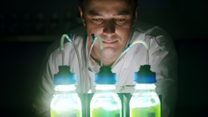 Person in front of 3 bottles illuminated by the contents of the bottles.