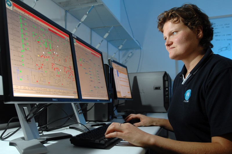 A female scientist sitting at a bank of computer monitors