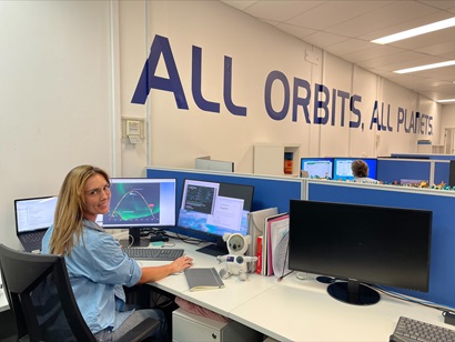Rosie Wall sitting at computer work station with two screens and laptop, screen display showing model of projection take off and landing for a rocket