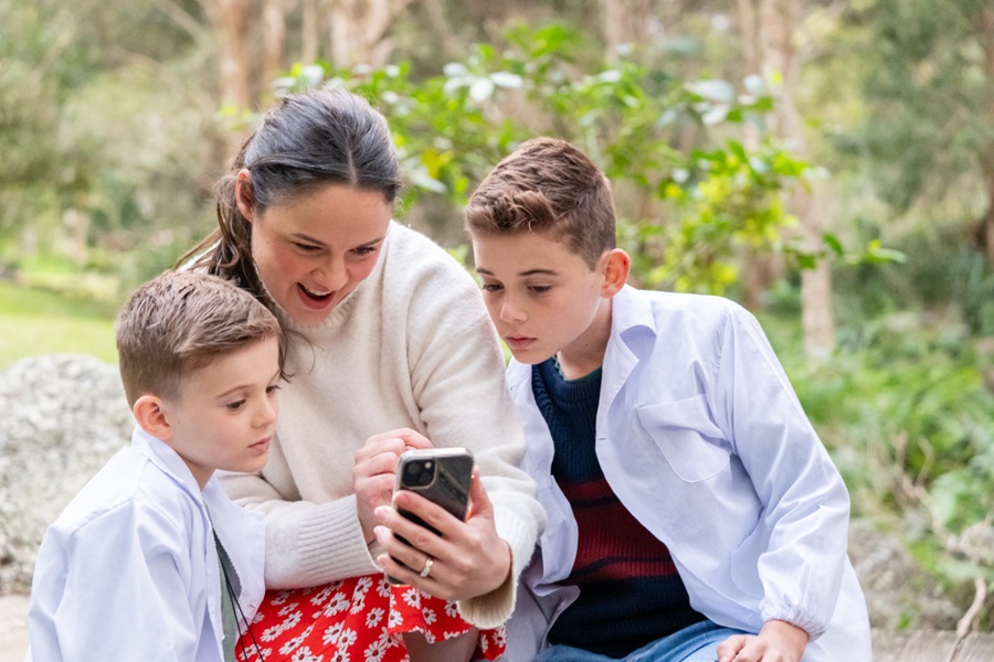 Mum and two boys looking at a phone together