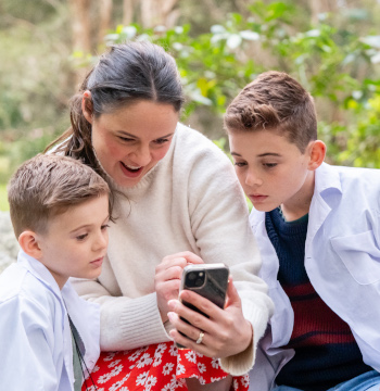 Mum and two young boys looking at phone. 