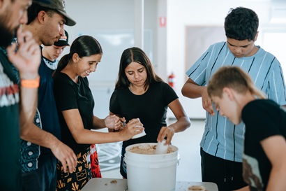 students coming together to build native bee hotels using sand and water