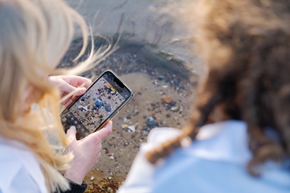 Two young people taking a photo of shells using a phone