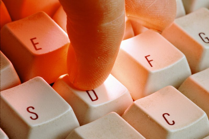 Closeup photo of a finger pressing a keyboard letter down