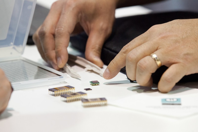 Photo of a person with tweezers picking up an integrated circuit