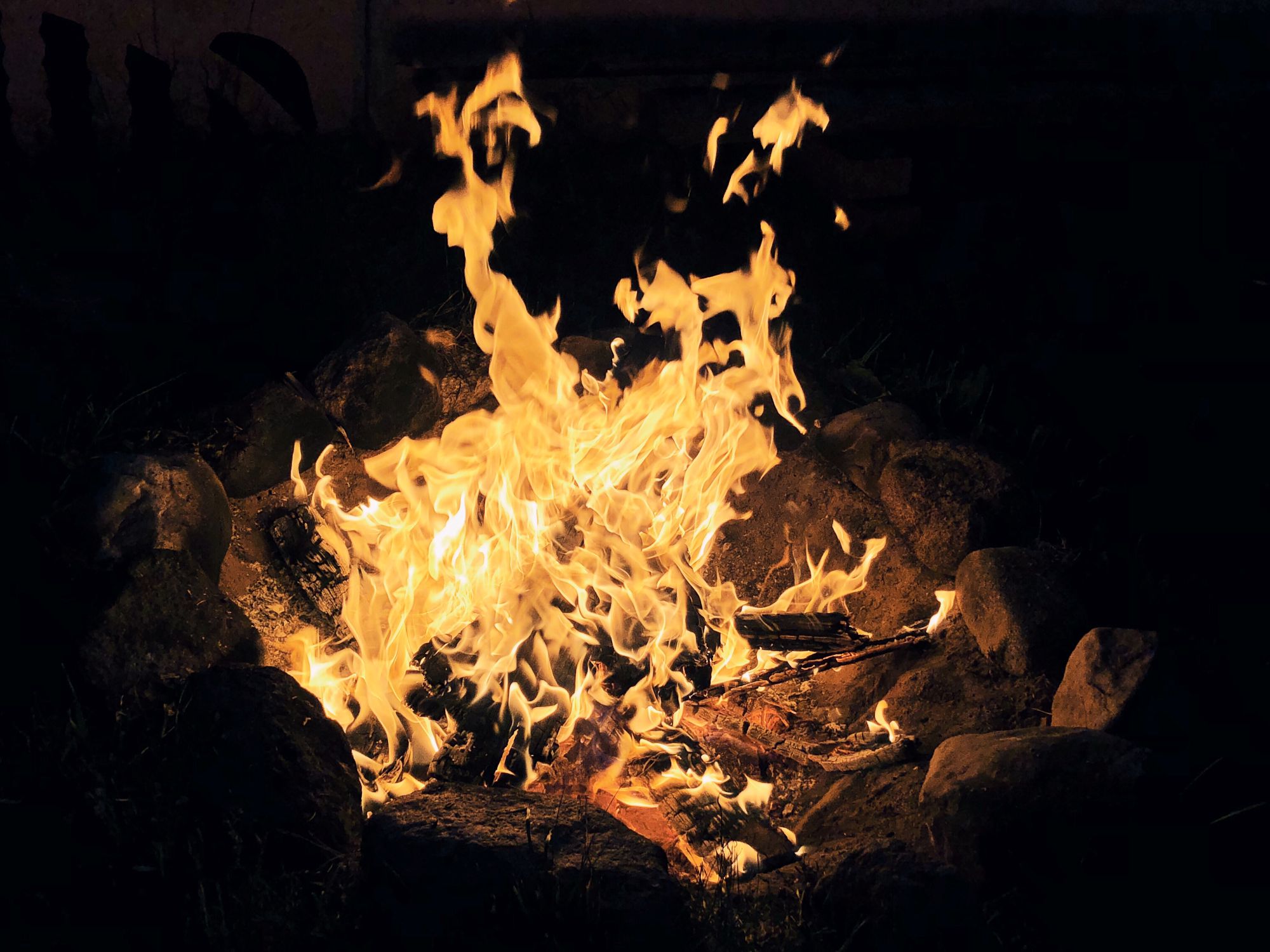 A bright yellow campfire illuminated at night in the Australian bush.