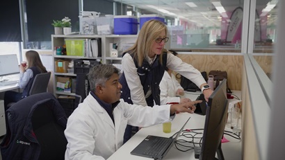Bronwyn Darlington standing at desk with colleague pointing at a computer.