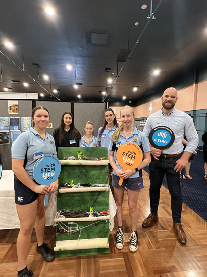 Students and a teacher holding 'With STEM you Can' signs at the Condobolin High School