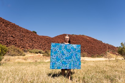 Photo of an artist holding her painting in outback Australia.