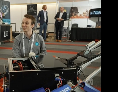 Smiling man seated behind a robotics contraption