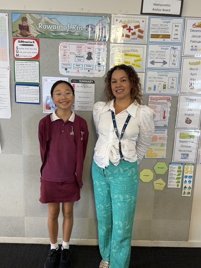 A girl in a school uniform standing alongside an adult woman both smiling into the camera