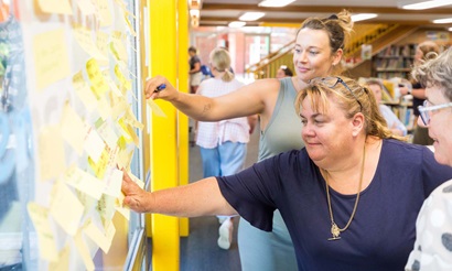 Teachers add their ideas, written on post it notes, to a wall as part of a Educator PL session
