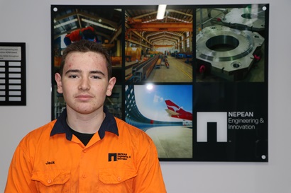 Jack Kennedy standing in front of a digital screen displaying various images for Nepean Engineering and Innovation.