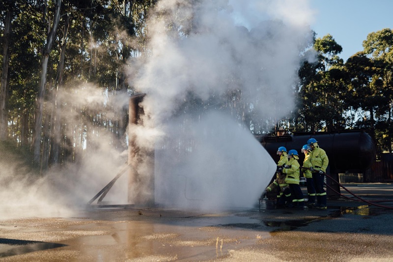Smoke and people using a fire hose