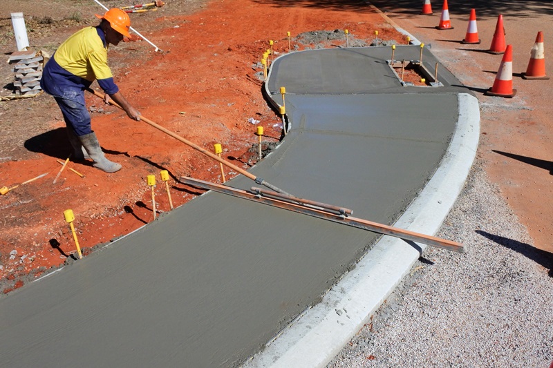 Australian road worker levelling a concrete sidewalk