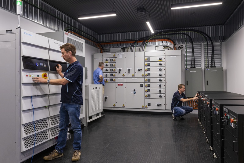 Two men working in a lab, one standing next to machine, another squatting next to a machine.