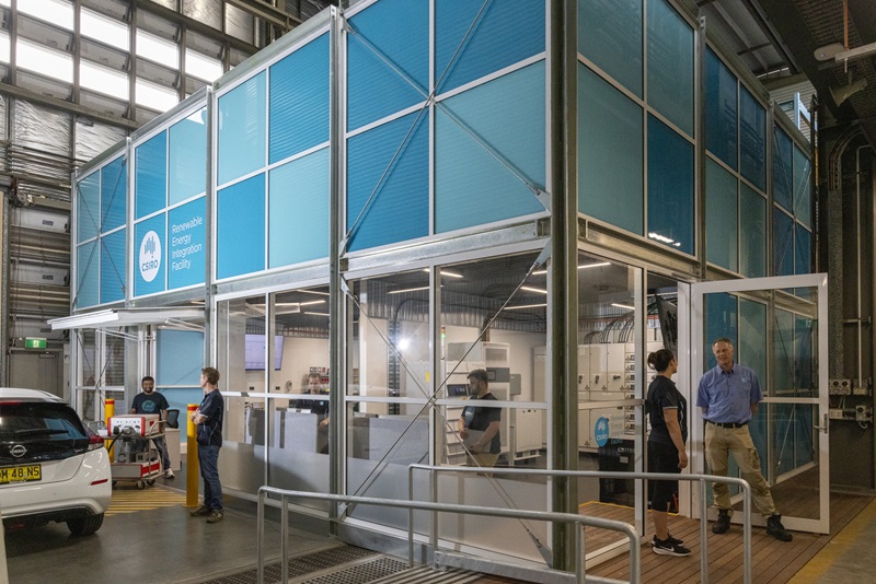 Inside a warehouse, workers chat with each other next to and inside a facility. 