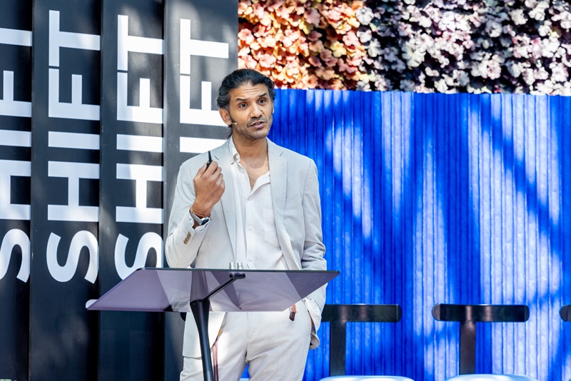 Man on stage in front of a lectern and a SHIFT banner.