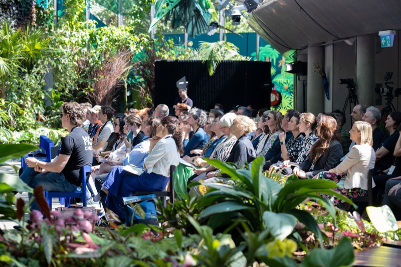 Audience sitting in chairs in a garden theatre.