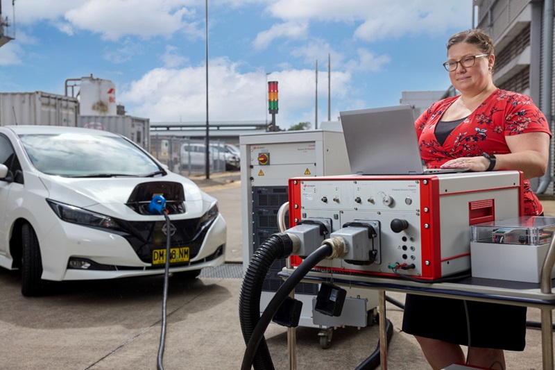 Kate Cavanagh working on computer in front of electric vehicle charging technology