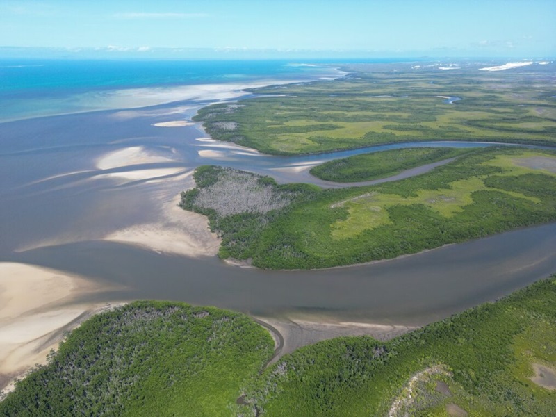 An estuary surrounded by grass and mountains.