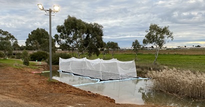 Pictured is constructed floating wetland on an urban stormwater stream channel, Salisbury, South Australia. The CFW is protected by mesh and sits over a small body of water.