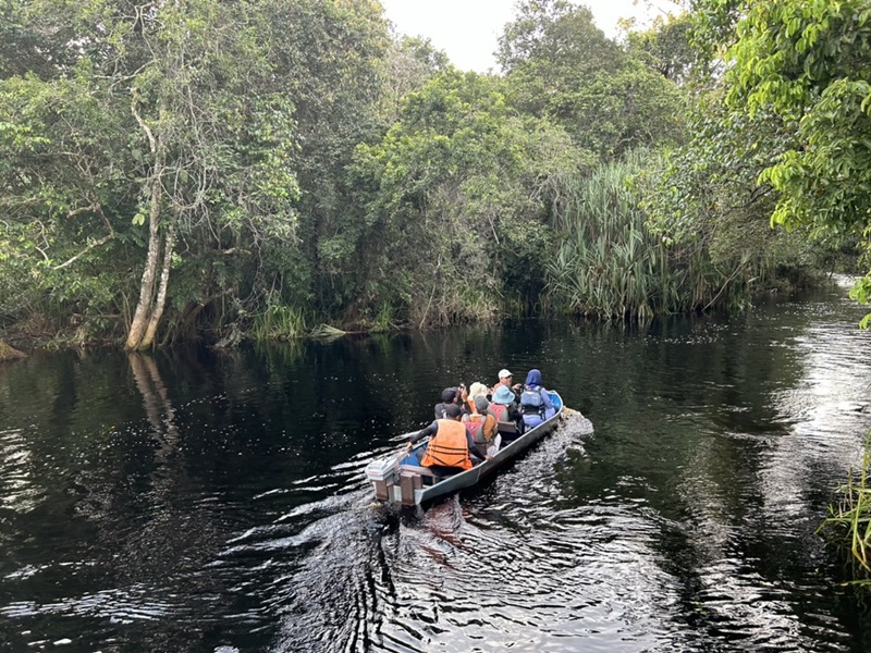 A small motor boat passes along a river between peatland